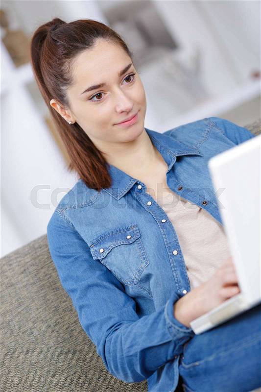 Happy girl sitting on couch with laptop, stock photo