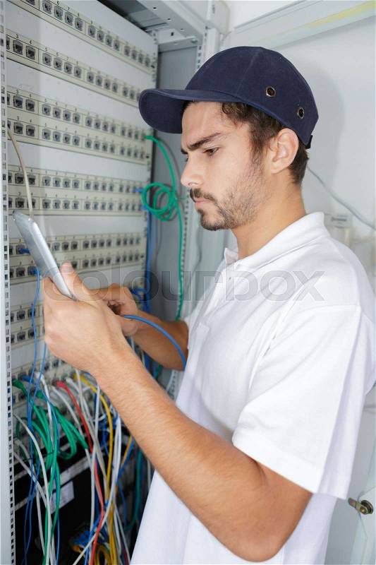 Focused electrician applying safety procedure while working on electrical panel, stock photo