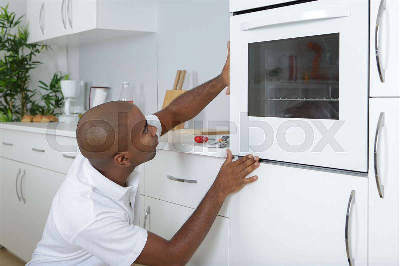 Man fitting oven into new kitchen, stock photo