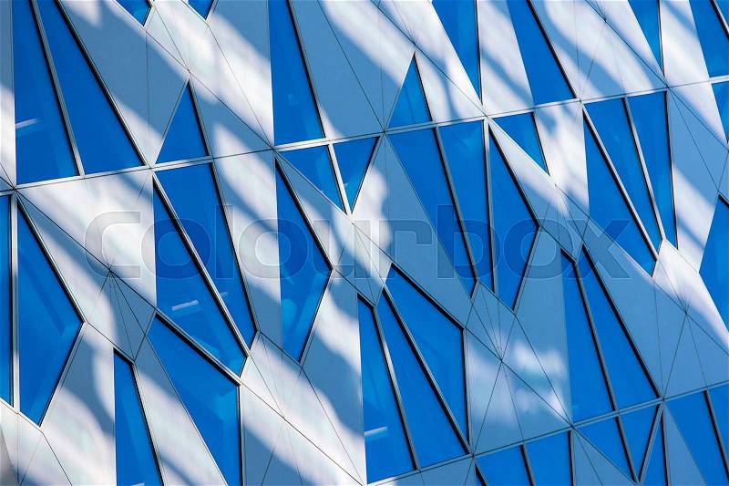 Blue toned sky reflection in the building window with sun and lens flare effect adde in Oslo, Norway, stock photo