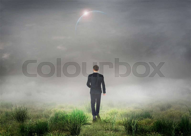 The concept of the unknown. Man in suit walk in fog on grass field. Concept of search the way, stock photo