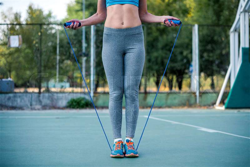 Woman in sportswear exercising with jump rope on the stadium , stock photo