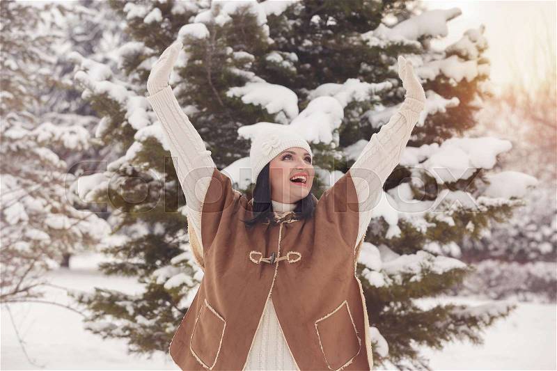 Beauty joyful woman raising hands and laughing outdoors in a sunny winter day, vintage toning image, copy space, stock photo