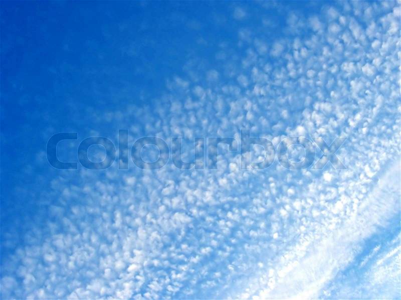 Fluffy cotton like clouds spread across a bright blue sky, stock photo