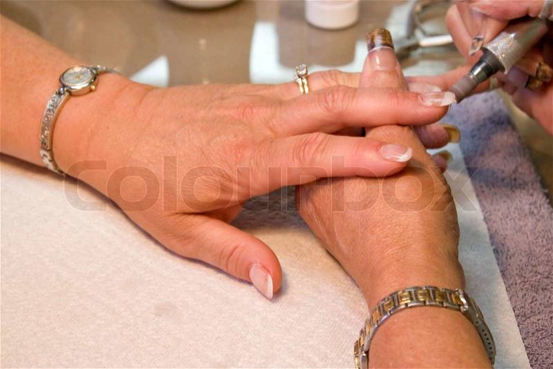 A professional nail technician working on a clients nails with the sander, stock photo