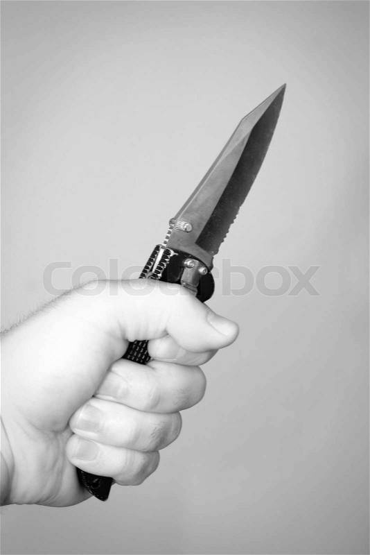 A hand gripping a scary looking knife, stock photo