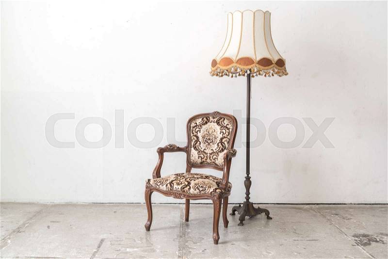 Brown vintage armchair and lamp on white wall, stock photo