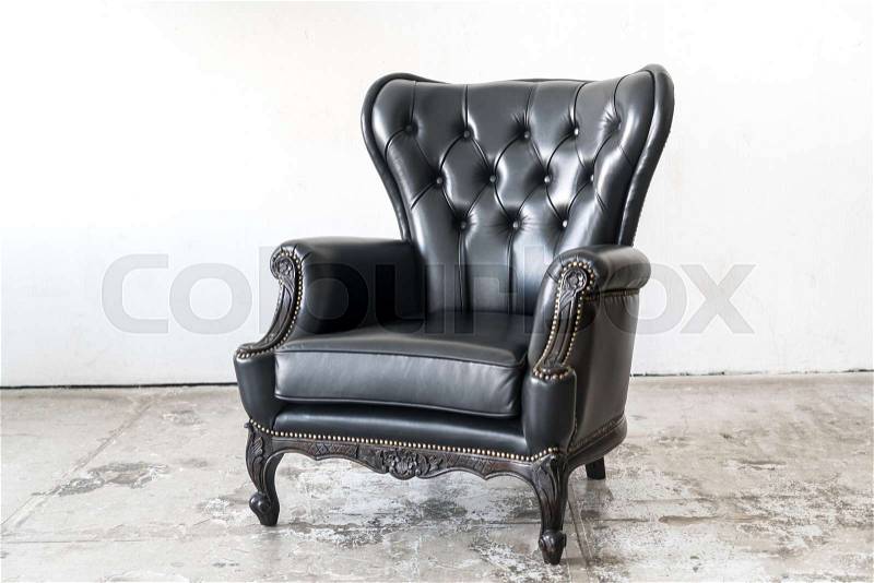 Black vintage armchair on white wall, stock photo