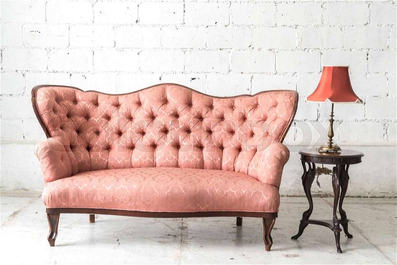Pink vintage sofa and lamp on white wall, stock photo