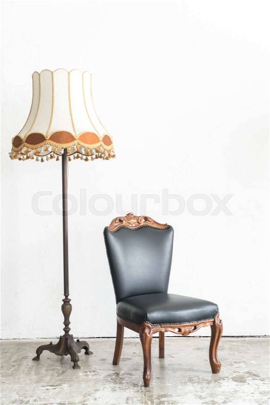 Black vintage armchair and lamp on white wall, stock photo