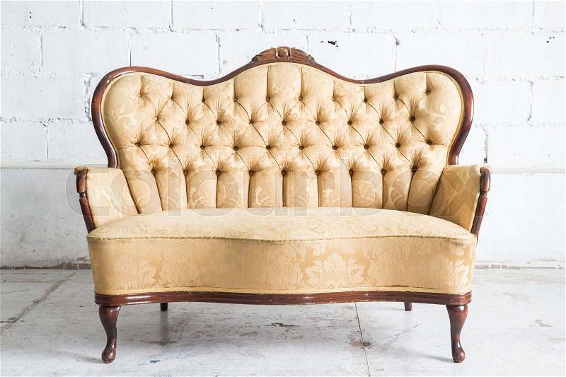 Yellow vintage sofa on white wall, stock photo