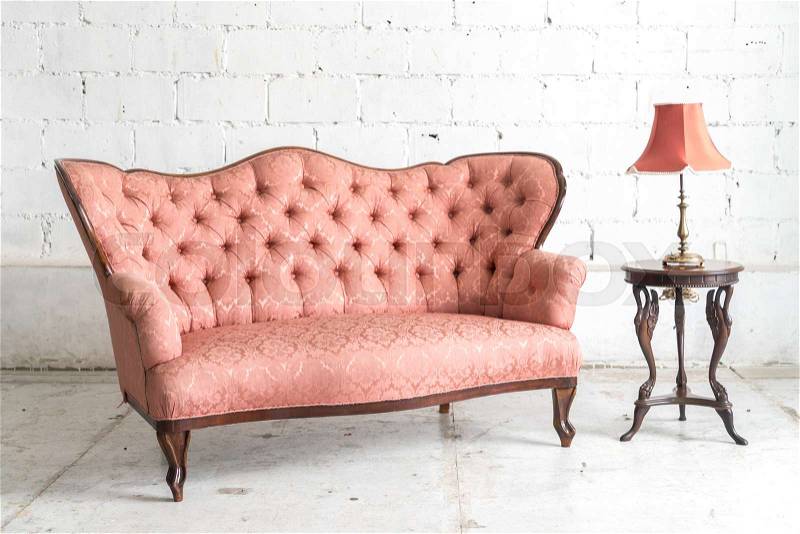 Pink vintage sofa and lamp on white wall, stock photo