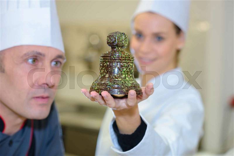 Portrait of two pastry chefs with chocolate bell, stock photo