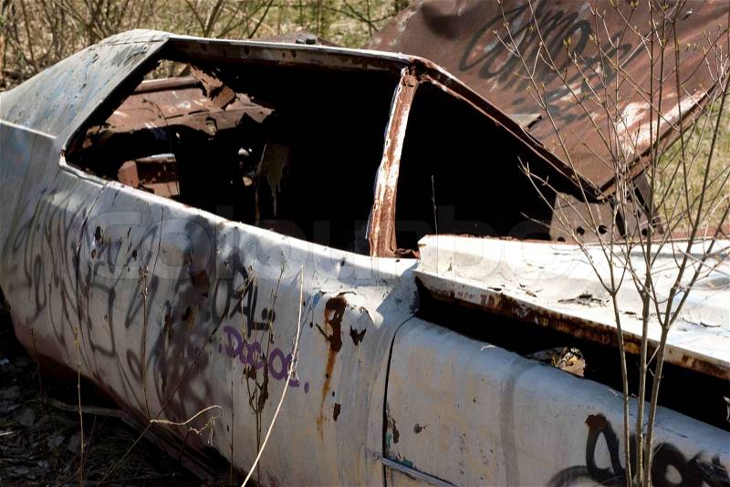 An old abandoned car body that is covered in graffiti, stock photo