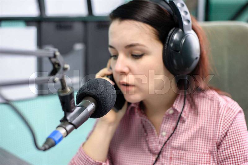 A radio DJ announces news in a radio-studio, stock photo