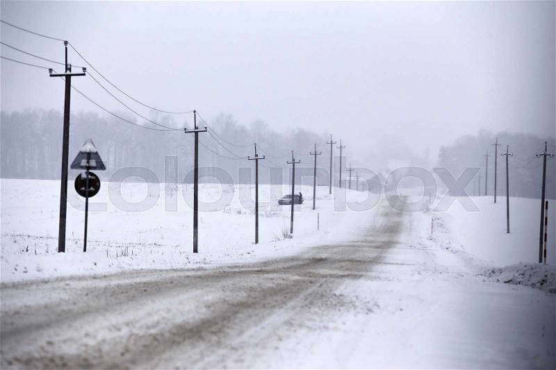 Snowfall and sleet on winter road. Ice snowy road. Winter snowstorm. Black ice and blizzard, stock photo