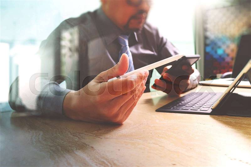 Businessman working with new start up project.using smart phone digital tablet docking smart keyboard and laptop computer on marble desk,sun effect, stock photo
