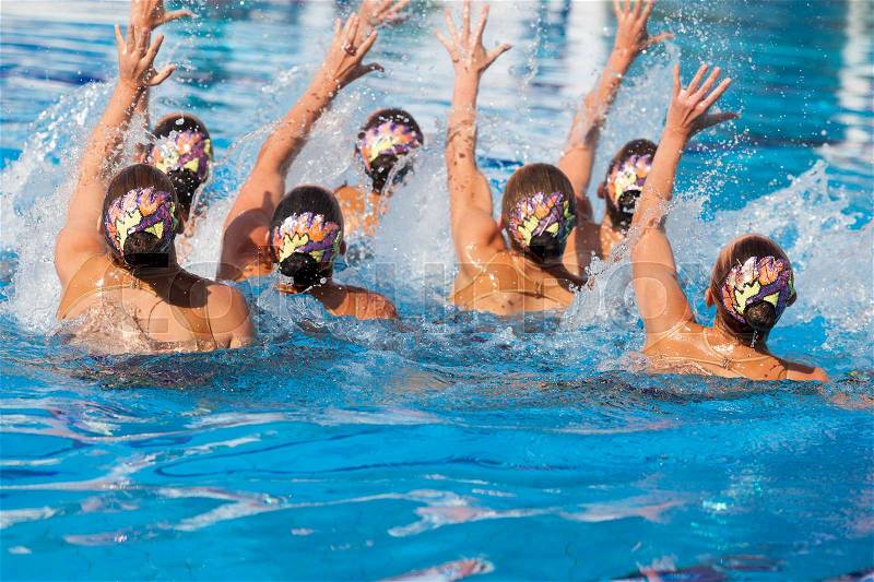 Synchronized swimming team performing a synchronized routine of elaborate moves in the water, stock photo
