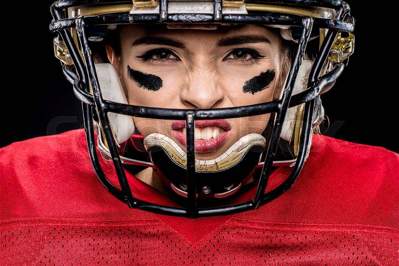 Close-up portrait of female american football player in sportswear and helmet on black, stock photo