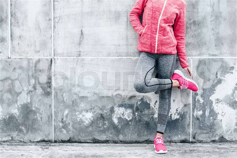 Fitness sport woman in fashion sportswear doing yoga fitness exercise in the city street over gray concrete background. Outdoor sports clothing and shoes, urban style, stock photo
