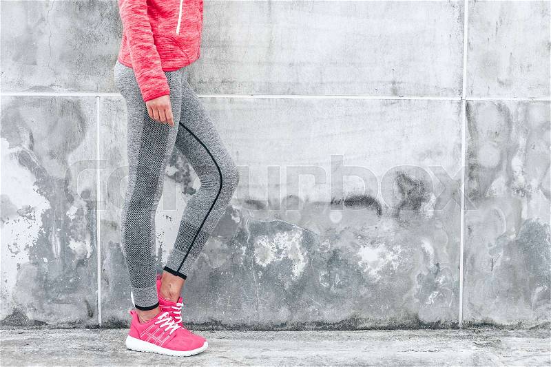 Fitness sport woman in fashion sportswear doing yoga fitness exercise in the city street over gray concrete background. Outdoor sports clothing and shoes, urban style, stock photo