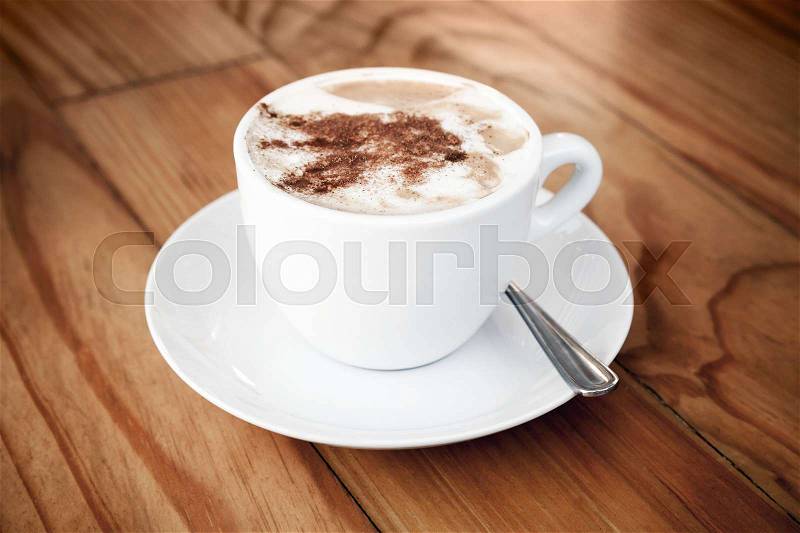 Cappuccino. Cup of coffee with milk foam and cinnamon stands on wooden table, stock photo