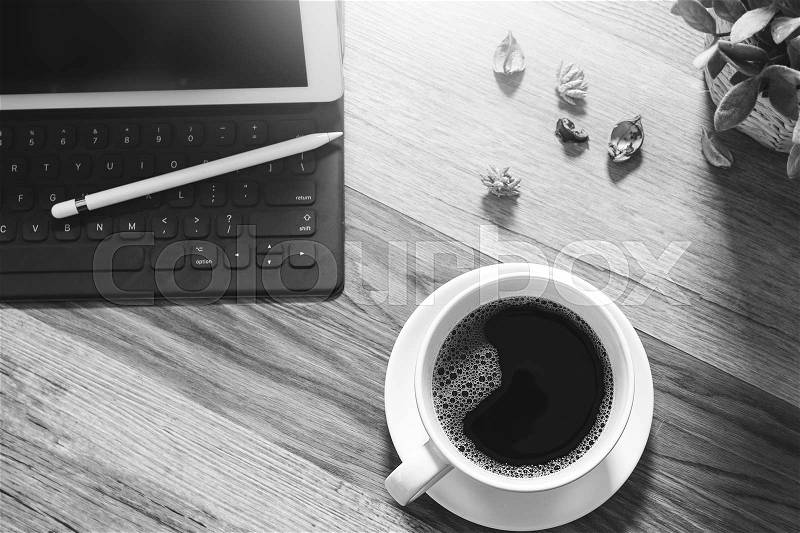 Coffee cup and Digital table dock smart keyboard,vase flower herbs,stylus pen on wooden table,filter effect,black white, stock photo