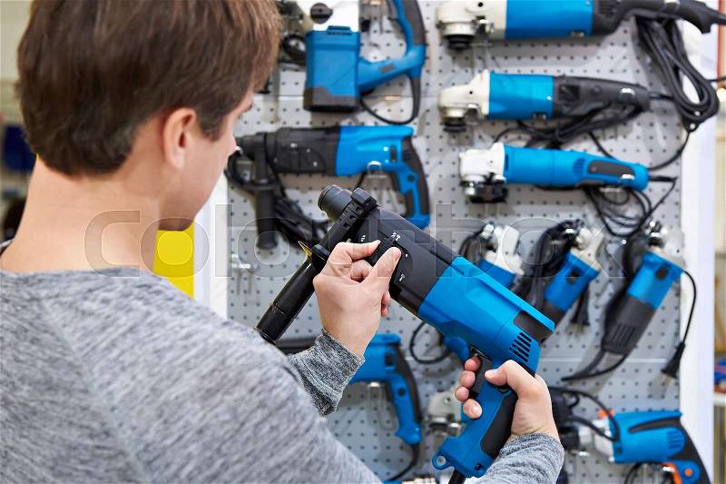 Man shopping for hammer drill in hardware store closeup, stock photo