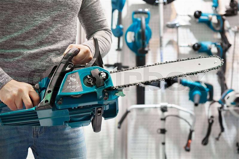 Chain saw in hands at store closeup, stock photo