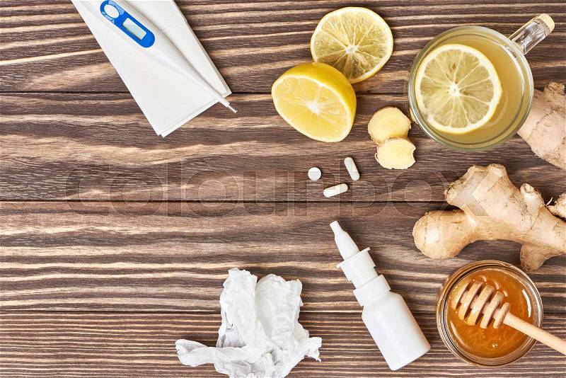 Cup of ginger tea, honey, lemon, pills, thermometer on wooden background. Healthy concep, stock photo