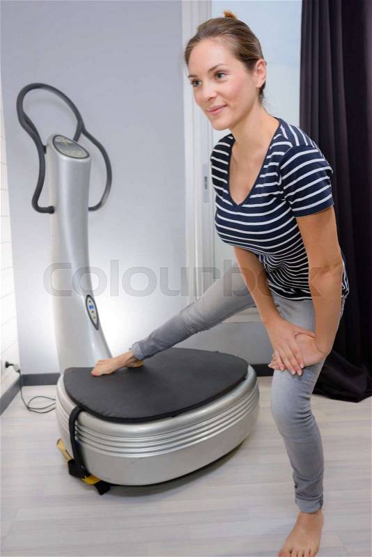 Woman exercising against step machine, stock photo