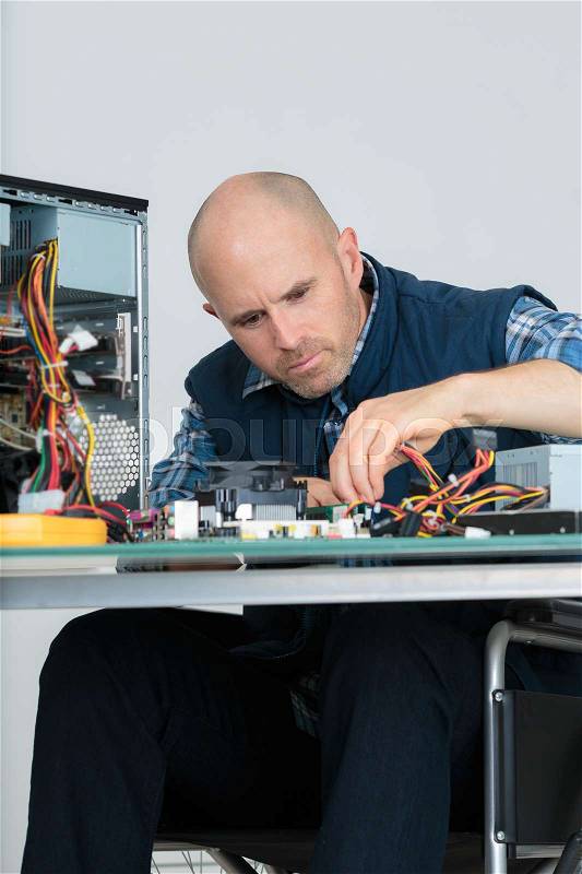 Computer engineer repairing computer in workshop, stock photo