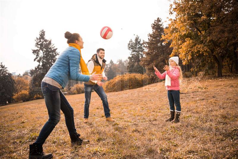 Happy family playing with ball in autumn park, stock photo