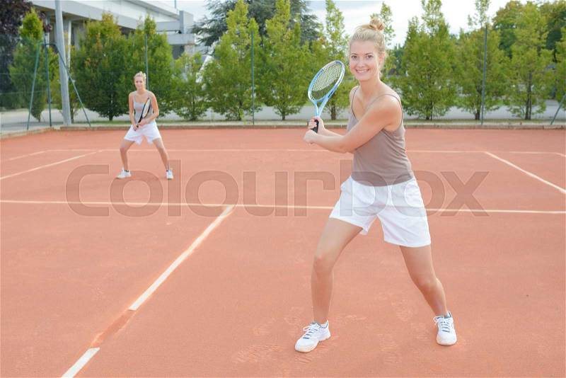 Women playing tennis doubles, stock photo