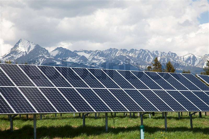 Solar panels on solar power station in Slovakia. Snow covered mountains and white clouds in the background. Green and environmentally friendly sources of energy, stock photo