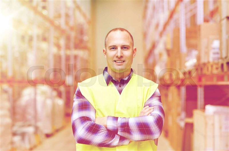 Wholesale, logistic, people and export concept - happy man in reflective safety vest at warehouse, stock photo