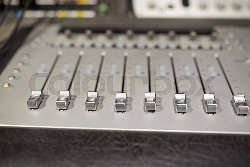 Music, technology, electronics and equipment concept - mixing console at sound recording studio, stock photo