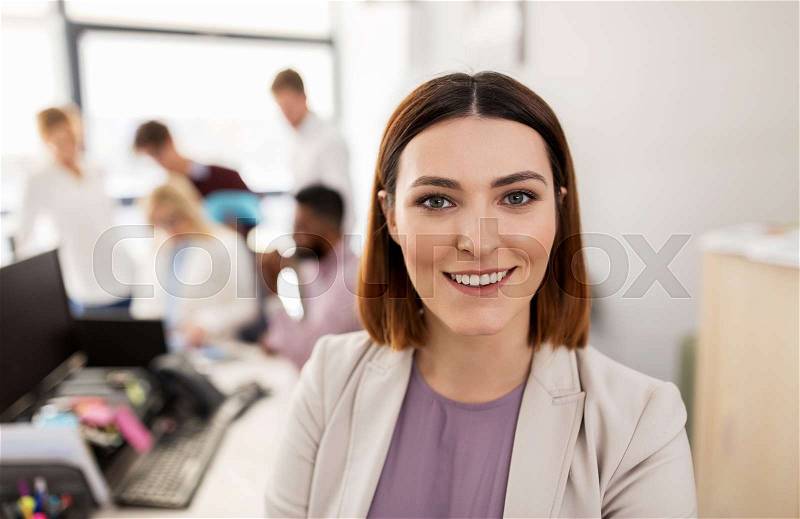 Business, startup, people and teamwork concept - happy woman over creative team in office, stock photo