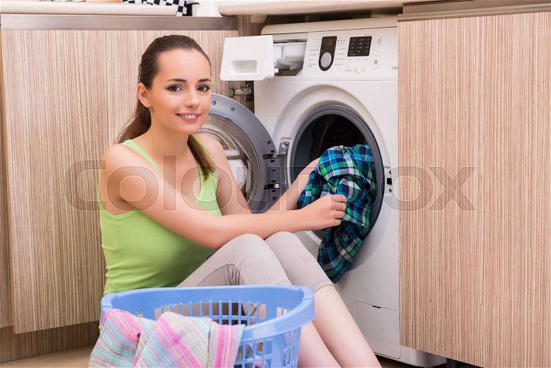 Young wife woman washing clothes near machine, stock photo