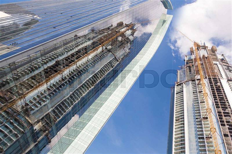 Huge skyscrappers construction site with cranes on top of buildings. Rapid urban and construction sector development or inflation of real estate bubble, stock photo