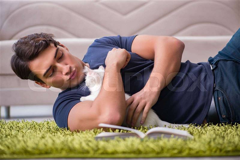 Young handsome man playing with white kitten, stock photo