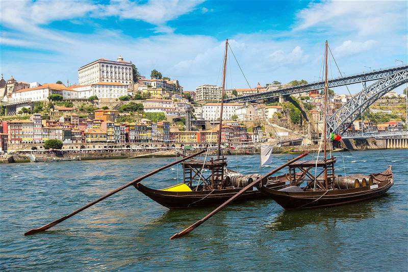 Traditional boats with wine barrels and Douro River in Porto in a beautiful summer day, Portugal, stock photo