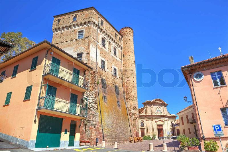 Small plaza surrounded by ancient castle, old church and city hall building in Roddi - small town in Piedmont, northern Italy, stock photo