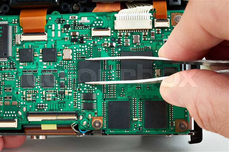 Repair microchip on electronic board of photo DSLR camera in service closeup, stock photo