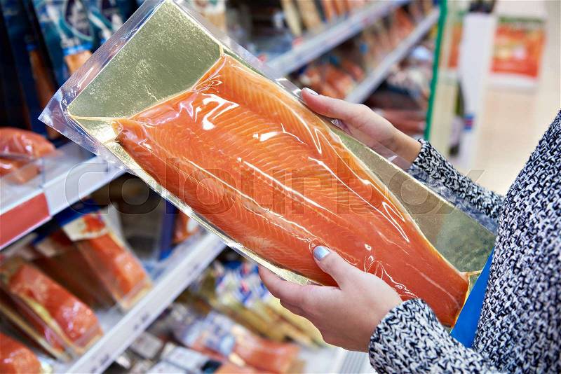 Woman buys in the supermarket salted salmon, stock photo