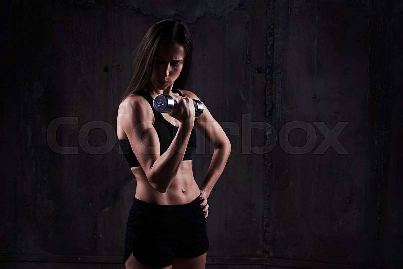 Close-up of serious woman doing biceps exercise with right breathing. Sporty young woman doing exercise. Woman training with dumbbells. Caucasian sport girl training hard, stock photo
