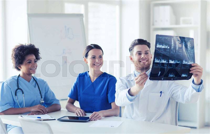 Radiology, people and medicine concept - group of happy doctors looking to and discussing x-ray image at hospital, stock photo