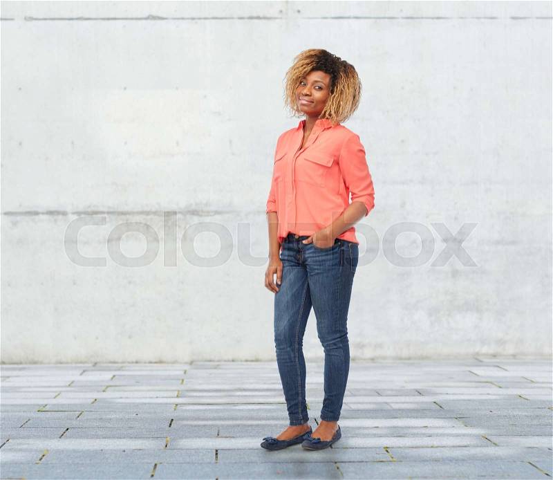 People, race, ethnicity and portrait concept - happy african american young woman over stone wall background, stock photo