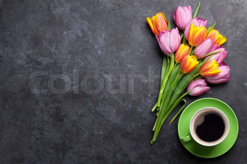 Fresh colorful tulip flowers and coffee cup on dark stone table. Top view with copy space, stock photo