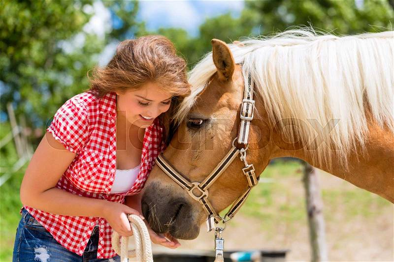 Woman feeding horse on pony farm, stock photo